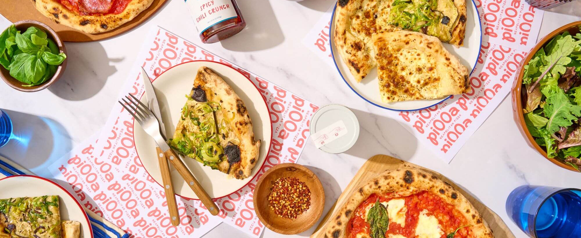Table with various pi00a,salads, and drinks on a patterned tablecloth.